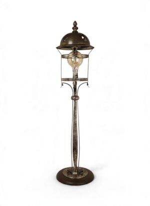 Tall Arts & Crafts-style silver-plated table lamp, c.1900–1920, featuring a pierced fleur-de-lis domed canopy, decorative floral finial, open cylindrical lantern framework, elegant scrolling metal supports and a circular wooden base, retaining a beautifully aged silver patina.